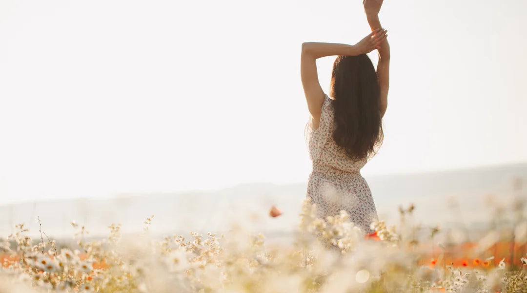 A woman in modest attire stands gracefully amidst a vibrant field of wildflowers, embodying faith and nature's beauty.